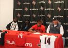 Dontavius Daniels (third from left) signs to play college football at Trinity Valley College in Athens at the Mexia High School field house Wednesday morning. Looking one are (from left) his dad David Daniels, his mom Denetra Jones, and Mexia High School football coach and athletic director Aaron Nowell.
